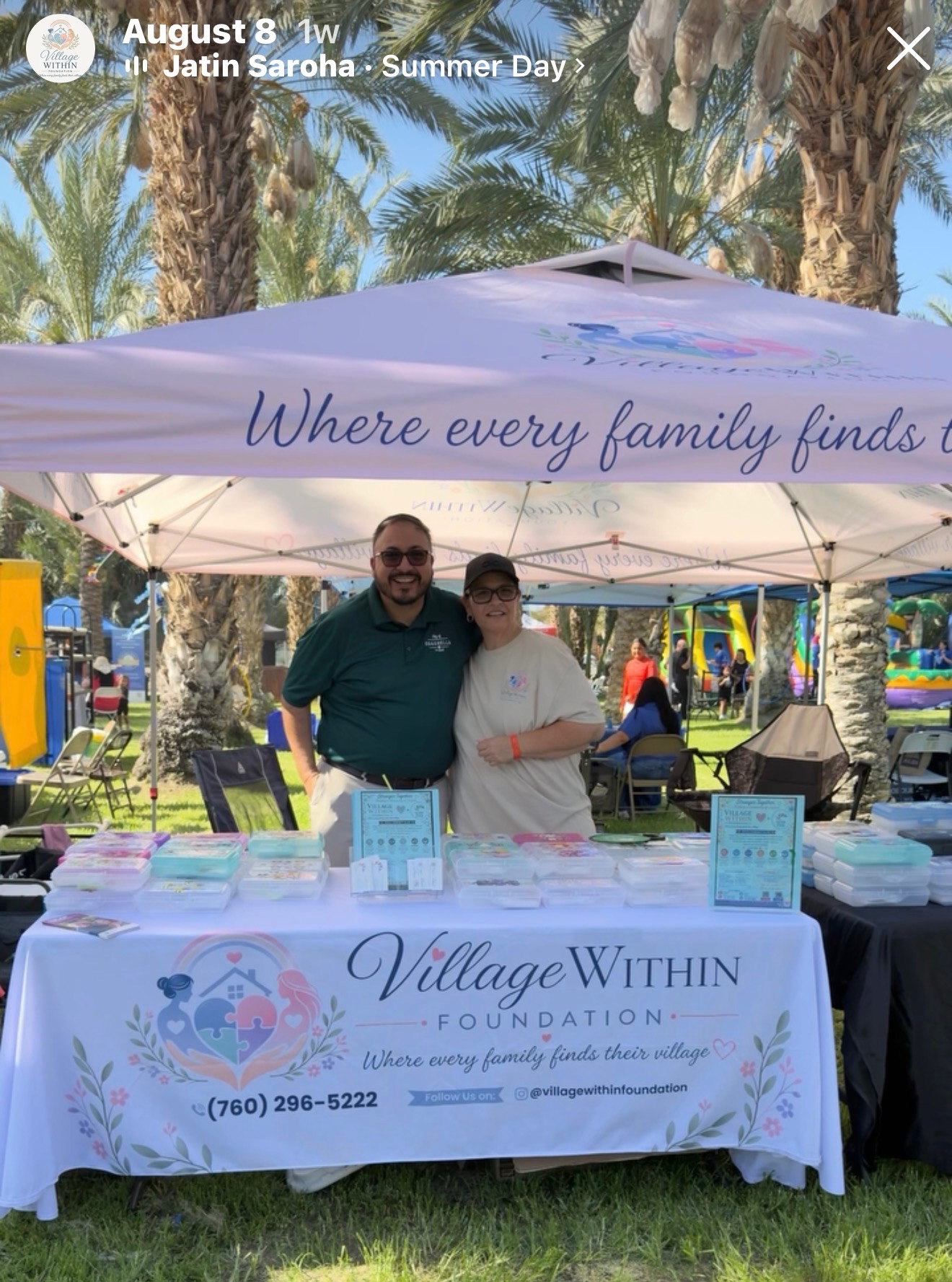 Two volunteers smiling behind the Village Within Foundation resource table